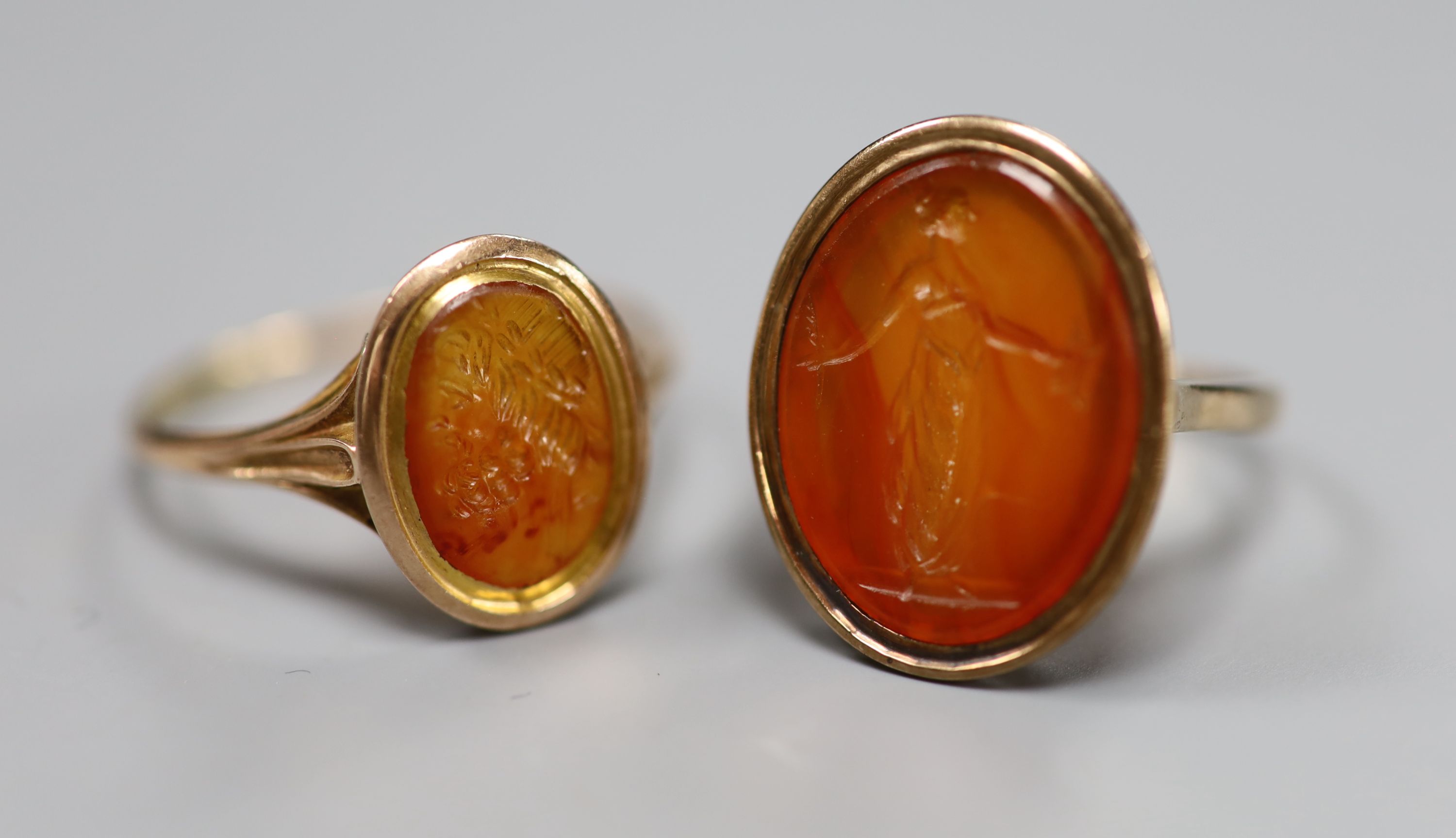 Two 19th century yellow metal and oval carnelian intaglio rings, carved with a bust or figure, one stamped 9ct,